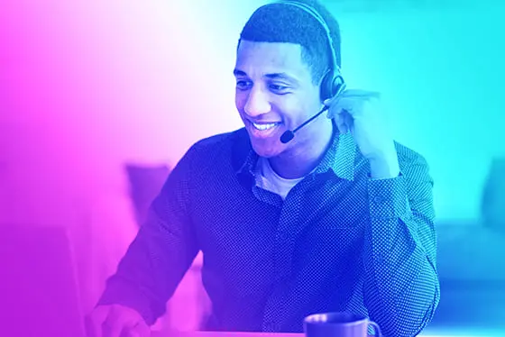 Homme souriant échangeant avec un stagiaire en formation e-learning avec son casque audio sur les oreilles et un micro